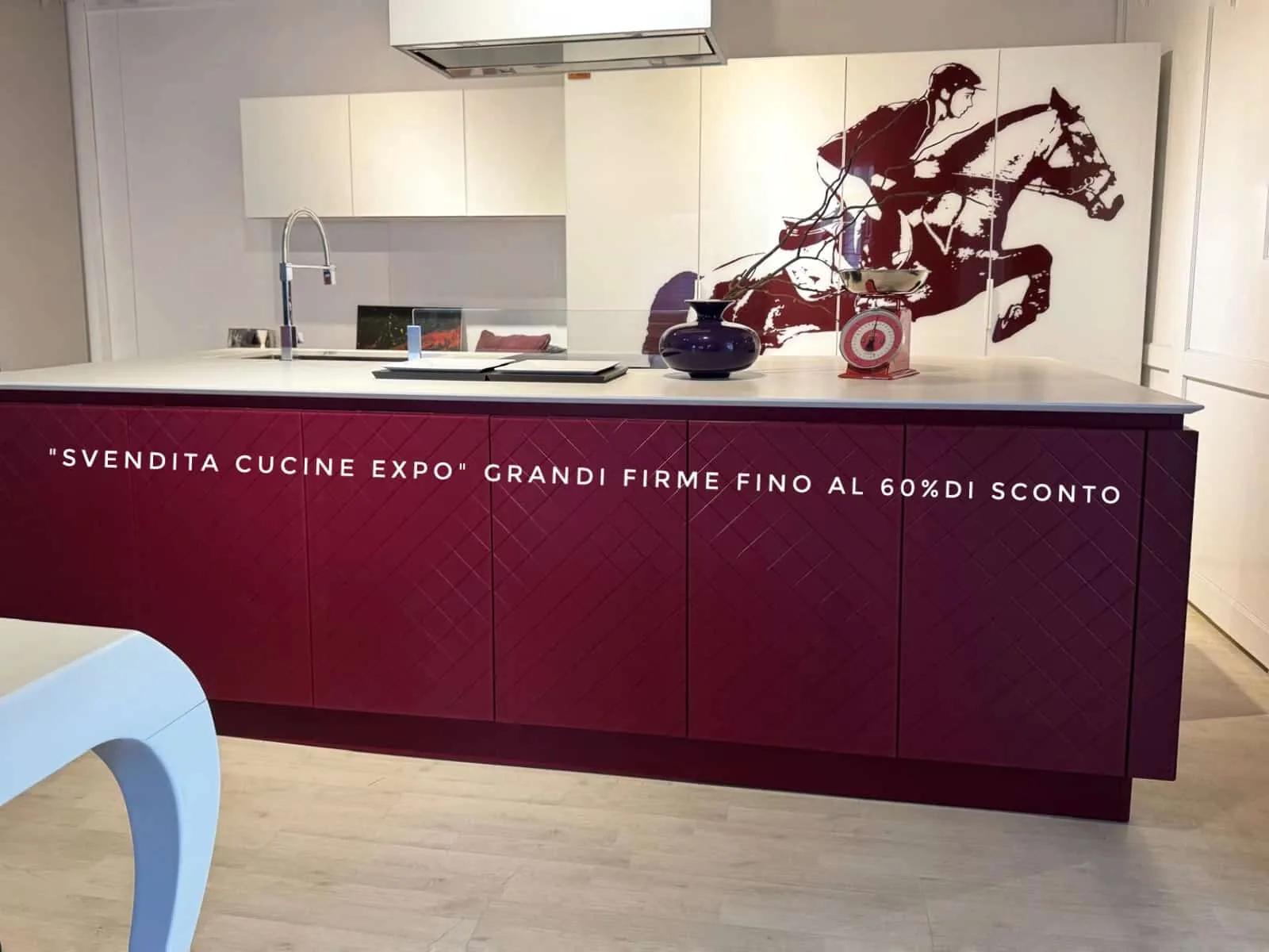 Vista frontale dell’isola rosso rubino in esposizione, con pensili bianchi e murale del cavallo