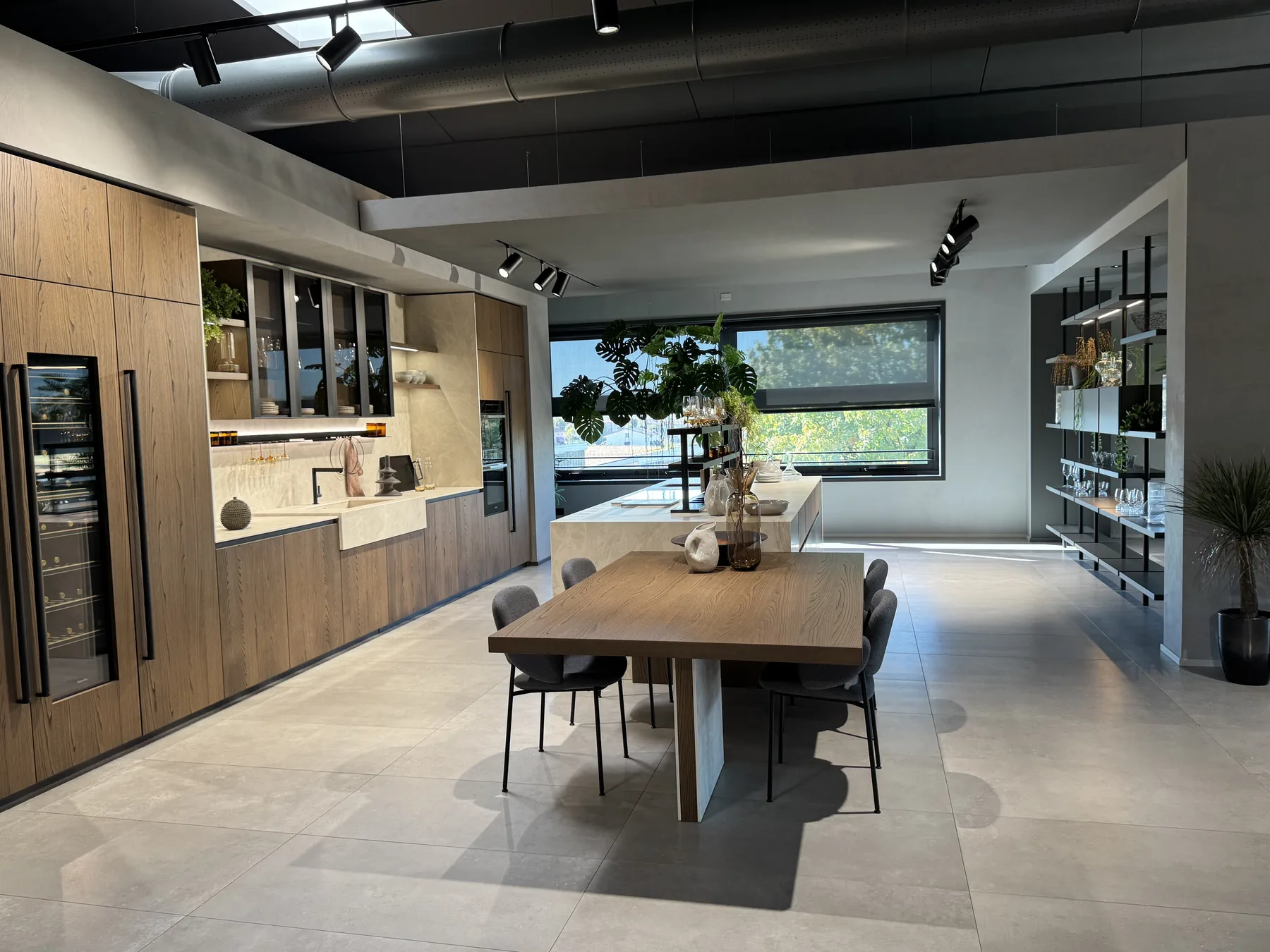 Interno dello showroom M3 Design con cucina in rovere, isola e tavolo da pranzo