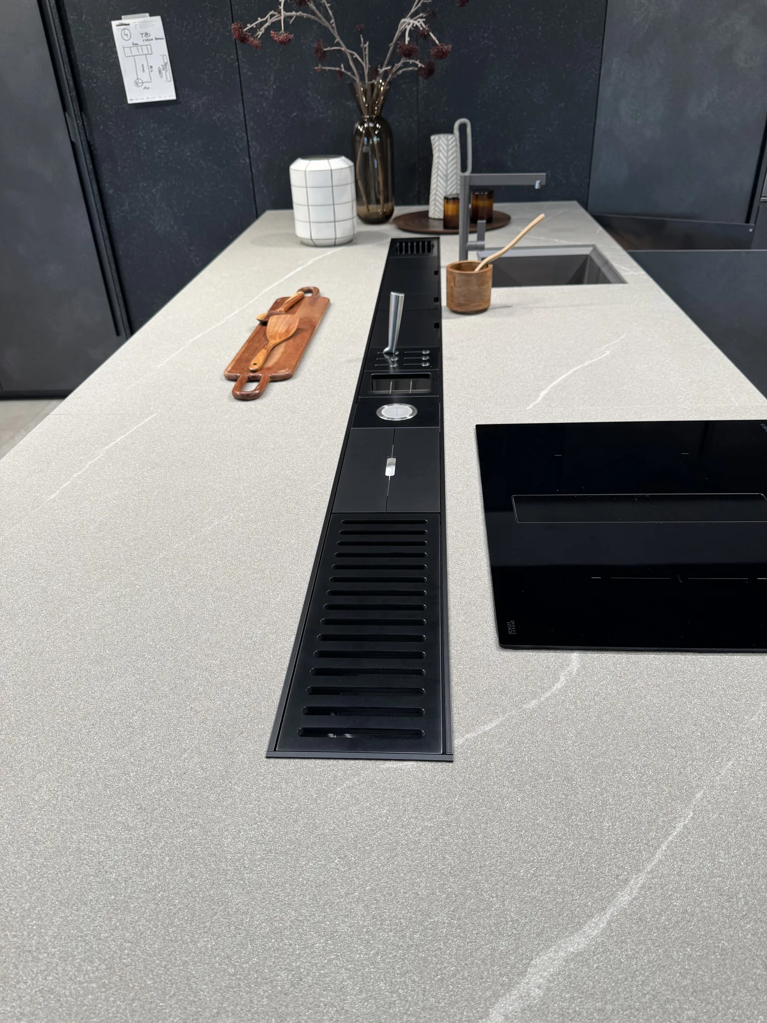 Top in Laminam Diamond Cream con canale attrezzato nero a filo, miscelatore e piano a induzione con aspirazione integrata